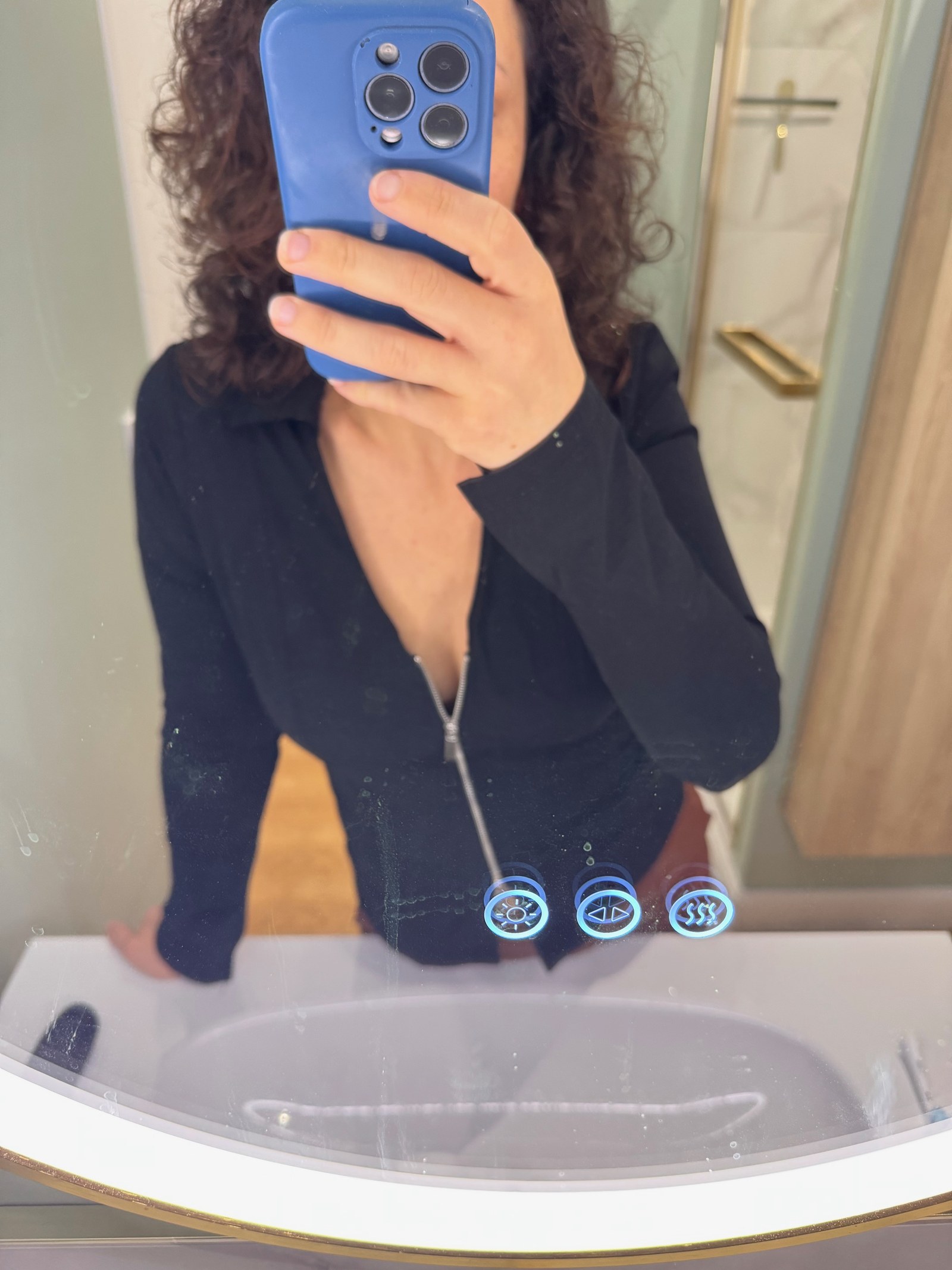 Klara tar en speilselfie i en svart genser med glidelås, mobilen foran ansiktet